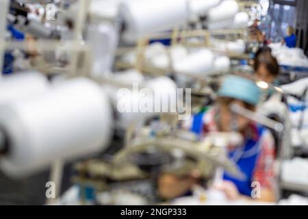 Sfocare lo sfondo con le donne sono impegnati nella sartoria di collant in una fabbrica Foto Stock