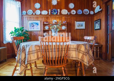 Antico tavolo in legno a forma ovale con sedie con schienale alto, buffet nella sala da pranzo con pavimento in legno di pino colombiano, pareti e soffitto all'interno della vecchia casa. Foto Stock