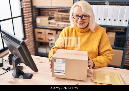 Donna bionda del Medio Evo ecommerce lavoratore di affari che tiene il pacchetto all'ufficio Foto Stock