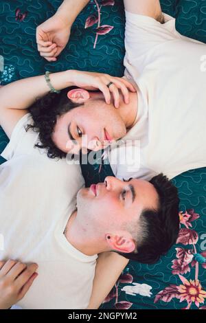 Appartamento di una coppia gay latino sdraiato sul letto e guardarsi l'un l'altro romanticamente. LGBT concetto di orgoglio Foto Stock