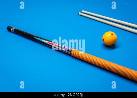 Bastoni e una palla gialla su un tavolo da biliardo. Foto Stock