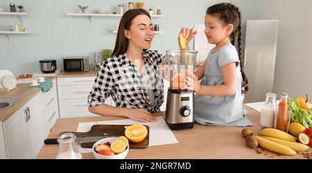 Madre e figlia piccola con moderno frullatore che rende sano frullato in cucina Foto Stock