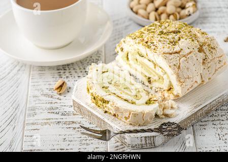 Meringa svizzera di albumi e zucchero al pistacchio, mascarpone. tazza di caffè nelle vicinanze Foto Stock