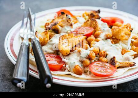 Burrito vegetale aperto con tortillas di farina, cavolo, cavolfiore arrosto, ceci arrosto e salsa piccante. Foto Stock