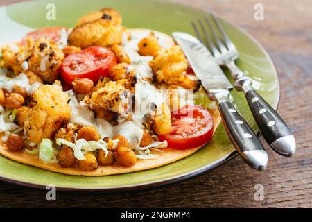 Burrito vegetale aperto con tortillas di farina, cavolo, cavolfiore arrosto, ceci arrosto e salsa piccante. Foto Stock