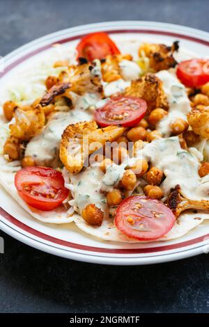 Burrito vegetale aperto con tortillas di farina, cavolo, cavolfiore arrosto, ceci arrosto e salsa piccante. Foto Stock