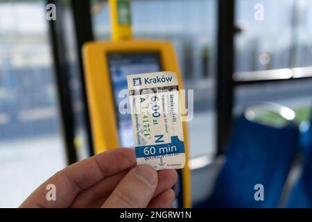 Una mano che tiene in mano un tipo di biglietto a tariffa intera di 60 minuti all'interno di un autobus di trasporto pubblico MPK Kraków, accanto alla macchina di convalida a Cracovia, Polonia. Foto Stock