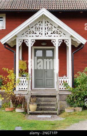 Ingresso scandinavo in legno rosso con facciata decorata in bianco Foto Stock