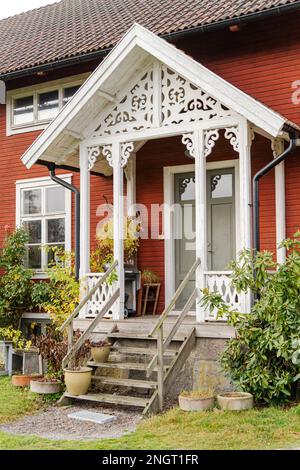 Ingresso scandinavo in legno rosso con facciata decorata in bianco Foto Stock