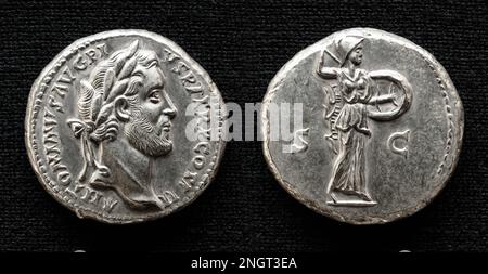 Antica moneta romana, denaro dell'imperatore Antonino Pio, dea Minerva sul retro. Macro vista del denario, vecchia moneta rara isolata su sfondo scuro Foto Stock