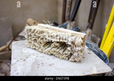 Primo piano, messa a fuoco selettiva su un pennello sintetico bianco usato. Questa spazzola viene utilizzata nell'industria edile durante l'intonacatura. Foto Stock