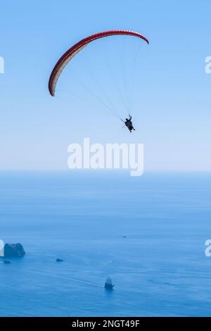 Parapendio nel cielo. Parapendio tandem volare sul mare con acqua blu, spiaggia e montagne sullo sfondo in Alanya Turchia. Foto Stock