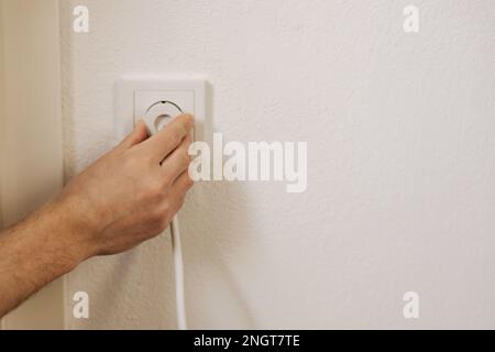 La vista in prima persona della mano dell'uomo inserisce il caricabatterie nella presa Foto Stock