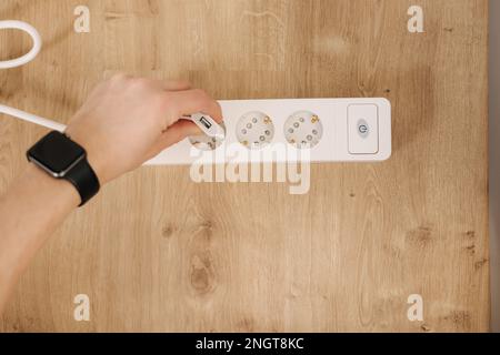 La vista dall'alto della mano maschio inserisce l'adattatore nella prolunga. Connettore cavo bianco Foto Stock