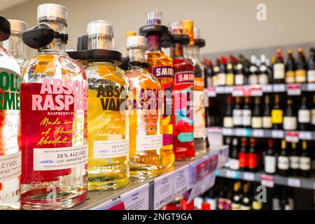 Fuoco poco profondo di una bevanda alcolica vicina da un marchio ben noto visto su uno scaffale del supermercato con i dispositivi di sicurezza attaccati. Foto Stock