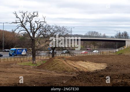 Datchet, Berkshire, Regno Unito. 17th febbraio, 2023. La mescola M4 di Datchet al confine con Slough, che è stata utilizzata per immagazzinare tutti i materiali delle opere di Smart Motorway, è attualmente in fase di smantellamento. Una trincea è stata scavata per seppellire il cablaggio. Enormi mucchi di terreno vengono rimossi e la recinzione protettiva intorno a due vecchi alberi di quercia è stata rimossa. La zona era precedentemente utilizzata come campi per il pascolo dei cavalli. Credito: Maureen McLean/Alamy Foto Stock