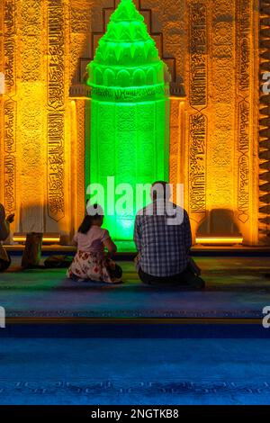 Foto di sfondo verticale islamico. Un uomo musulmano che prega e sua figlia o una bambina. Minbar sullo sfondo. Kandil o laylat al-qadr o kadir Foto Stock