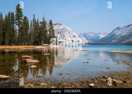 Riflessi perfetti delle montagne e degli alberi sul lago Tenaya, a Yosemite NP Foto Stock