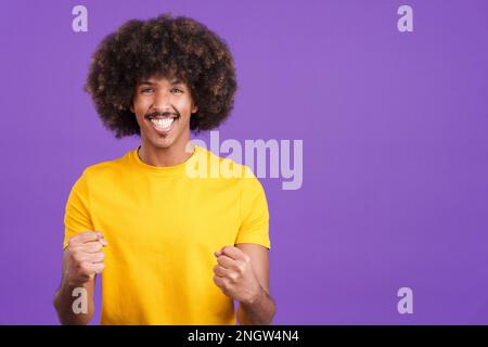 Felice uomo africano che guarda la macchina fotografica e festeggia Foto Stock