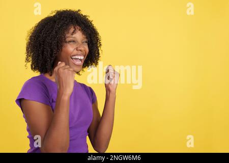 Donna felice con capelli afro festeggiando mentre alzando i pugni Foto Stock