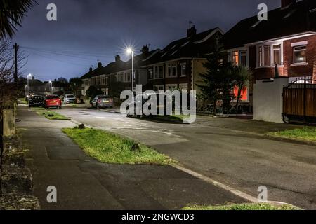 Strada di case di classe media con auto parcheggiate sulla strada nella periferia di Cardiff di notte Foto Stock