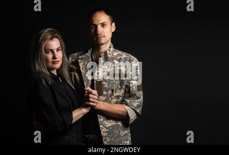 Donna felice abbraccia il suo marito è tornato dall esercito. Allegro sorridente ragazza caucasica abbracciando un soldato. Foto Stock