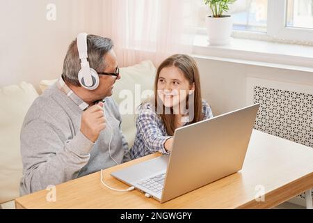 Nipote aiuta il nonno a comunicare on line sul laptop Foto Stock