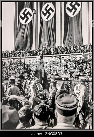 1934 Germania nazista propaganda Rally di Norimberga con 'la Consacrazione degli Standard'. Adolf Hitler in SA Sturmabbleitung uniforme con grande banner Swastika sullo sfondo Norimberga Germania nazista Foto Stock
