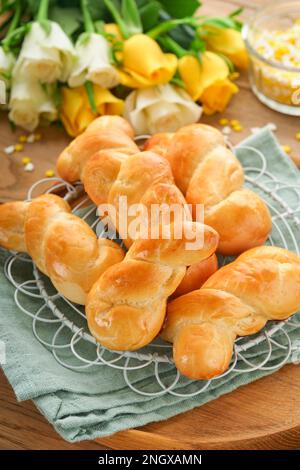 Colazione di Pasqua, concetto di Holliday. Panini di coniglietto pasquale con cannella a base di pasta di lievito con smalto arancione, decorazioni pasquali, uova colorate Foto Stock