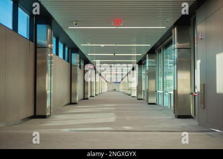 corridoio di edificio vuoto con segnaletica di uscita illuminata in rosso e finestre su un lato, non c'è gente Foto Stock