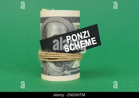 Concetto aziendale. Su una superficie verde, ha rotolato i dollari con un segno nero che dice - SCHEMA DI PONZI Foto Stock