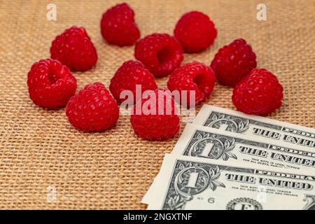 Lamponi rossi freschi con denaro contante. Coltivazione di lamponi, prezzo e concetto di cibo biologico. Foto Stock