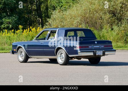 Un blu scuro 1982 Chrysler New Yorker Fifth Avenue Edition vista posteriore contro gli alberi in sole brillante. Foto Stock