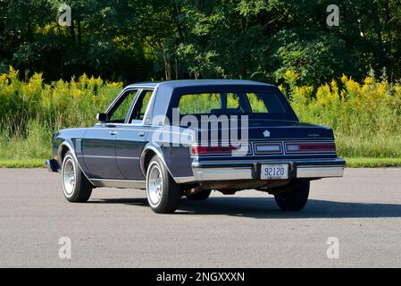 Un blu scuro 1982 Chrysler New Yorker Fifth Avenue Edition vista posteriore contro gli alberi in sole brillante. Foto Stock