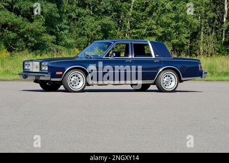 Un blu scuro 1982 Chrysler New Yorker Fifth Avenue Edition vista frontale contro gli alberi in sole luminoso. Foto Stock