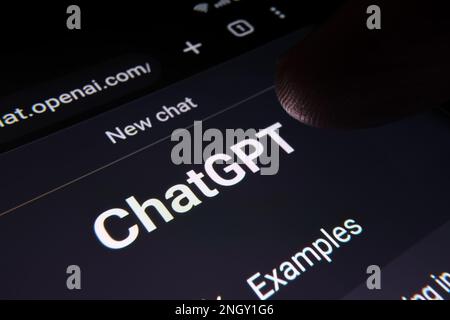 Il dito che tocca lo schermo del bot della chat di ChatGPT visto sul display dello smartphone con il grande logo di Chat GPT. Ai chatbot di OpenAI. Foto macro. Stafford, Regno Unito Foto Stock