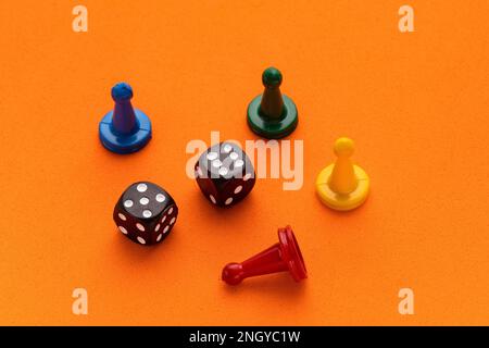 Le fiche di gioco colorate e due dadi sono collocati su uno sfondo arancione Foto Stock