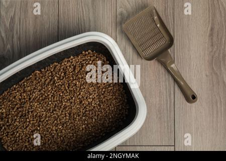 Vassoio Cat con lettiera biodegradabile e paletta su pavimento in legno, vista dall'alto Foto Stock