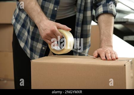 Uomo che nastrano scatola di cartone all'interno, vista primo piano Foto Stock