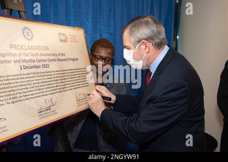 Sig.ra Melinda Deloatch-Speight, Stati Uniti Il coniuge della Guardia Costiera, guarda come il Dr. Douglas Lowy, direttore principale, U. S. National Cancer Institute (NCI), firma un annuncio in onore del 10th° anniversario del Murtha Cancer Center durante la celebrazione del 10° anniversario del centro oncologico, il 2 dicembre. Nominato ex membro del Congresso, John P. Murtha (D-PA), MCC esegue ricerche sul cancro traduzionali, progettate per supportare in modo efficace ed efficiente una forza pronta per il settore medico, fornire servizi oncologici di livello mondiale per il sistema sanitario militare e collaborare con altre agenzie federali, la medicina civile Foto Stock