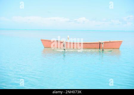 Canoe color arancio con vista sulle acque tropicali turchesi per riscaldare l'effetto shimmer su un orizzonte lontano. Foto Stock