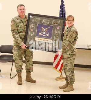 BASE COMUNE LEWIS-McChord, Washington. Aaron Palmquist (a sinistra) del 1-364th Battaglione di supporto alla formazione, 189th la Brigata di fanteria accetta un regalo di ritiro dal Lt. Col. Kristy Norquist (a destra), comandante del battaglione, per conto dell'unità durante una cerimonia per commemorare i suoi 40 anni di servizio presso il Centro della Riserva di Schwab a JBLM, Washington, 4 dicembre 2022. Foto Stock