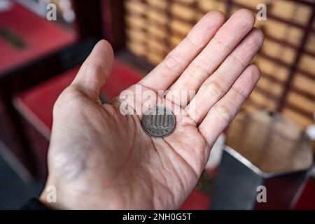 100 moneta di yen in mano maschile Foto Stock