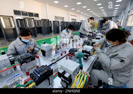 ZAOZHUANG, CINA - FEBBRAIO 20,2023 - lavoratori qualificati producono attrezzature di ricarica per veicoli a nuova energia in un'officina di un compan di produzione di attrezzature Foto Stock