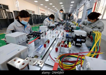 ZAOZHUANG, CINA - FEBBRAIO 20,2023 - lavoratori qualificati producono attrezzature di ricarica per veicoli a nuova energia in un'officina di un compan di produzione di attrezzature Foto Stock