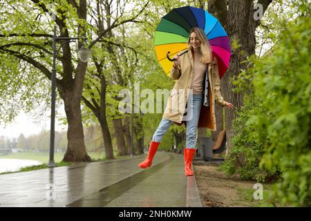 Giovane donna con ombrellone a piedi nel parco il giorno di primavera Foto Stock