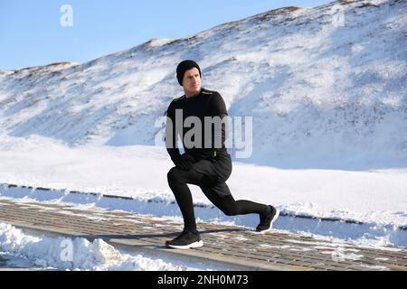 Uomo che fa esercizi sportivi all'aperto il giorno d'inverno Foto Stock