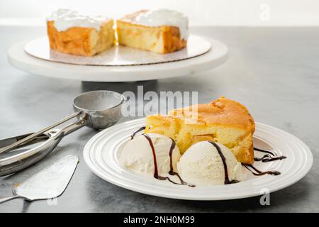 Fetta di una torta di mele appena sfornata con panna montata, servita con gelato alla vaniglia e primo piano al cioccolato su un piatto bianco Foto Stock