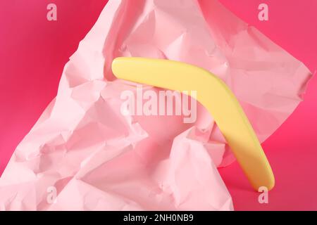 Composizione creativa con boomerang in legno giallo su sfondo rosa Foto Stock