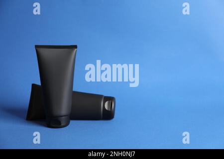 Tubi di creme facciali maschili su sfondo blu. Modello per il design Foto Stock
